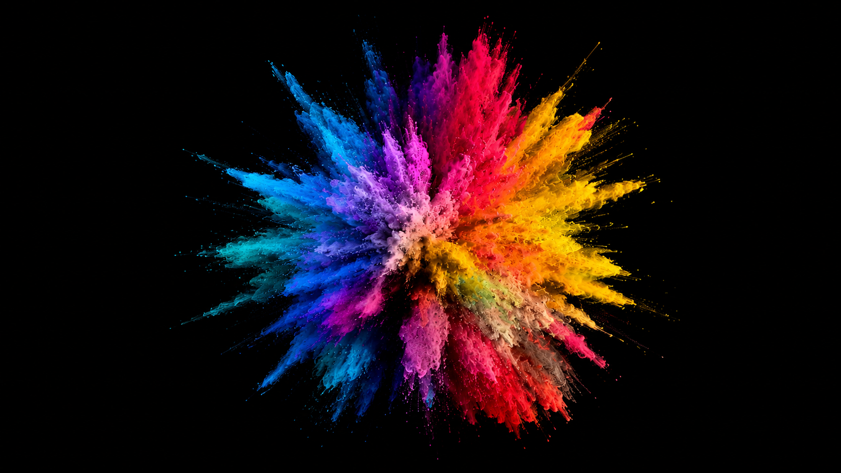 Un'esplosione vivace di polvere colorata si diffonde su uno sfondo nero, caratterizzata da tonalità brillanti di blu, rosa, rosso, giallo, arancione e viola, creando un motivo astratto di grande impatto visivo.