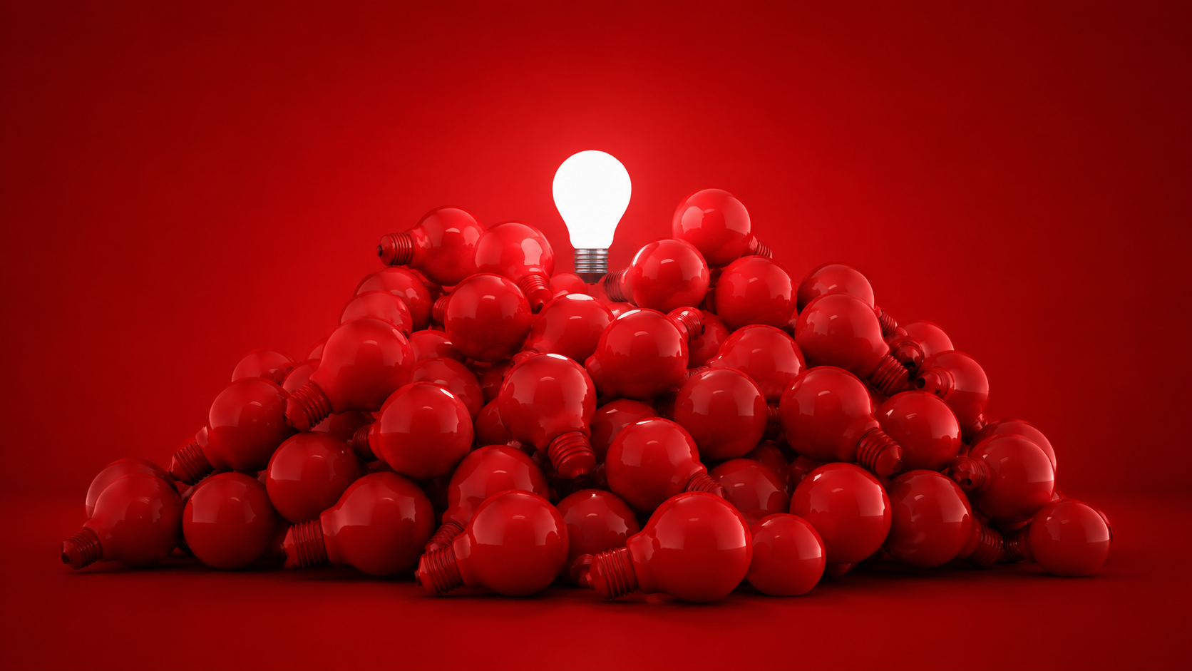 Una pila di lampadine rosse con una lampadina bianca in cima, accesa e luminosa, il tutto su uno sfondo rosso.