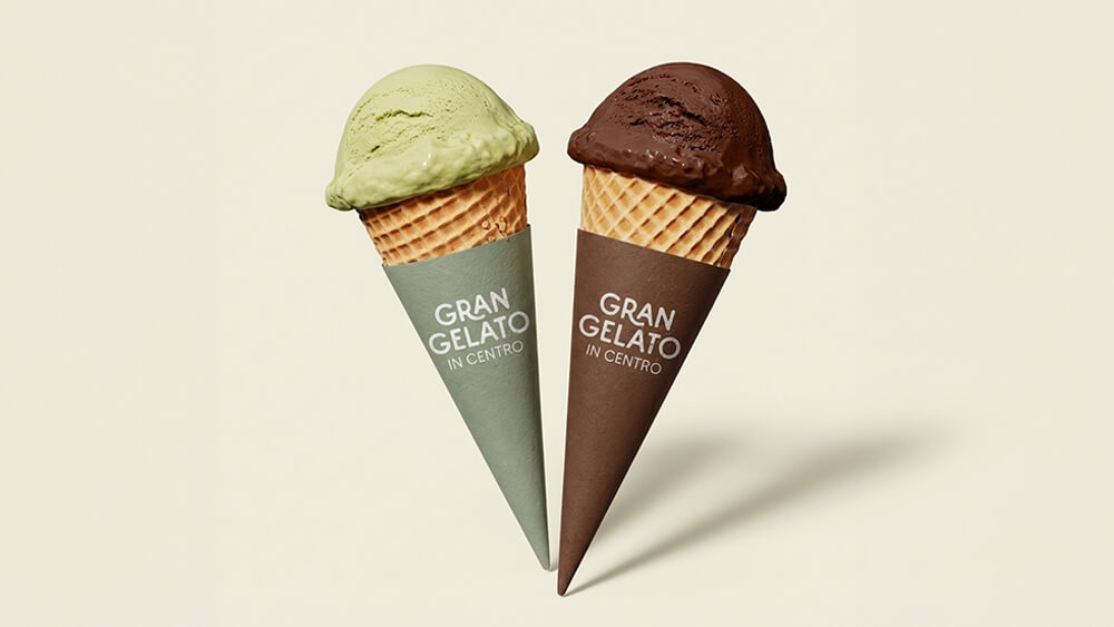 Sono raffigurati due coni gelato uno accanto all'altro. Uno contiene una pallina di gelato verde con un involucro verde chiaro, mentre l'altro contiene una pallina di gelato marrone scuro con un involucro marrone. Su entrambi gli involucri c'è scritto «GRAN GELATO IN CENTRO».